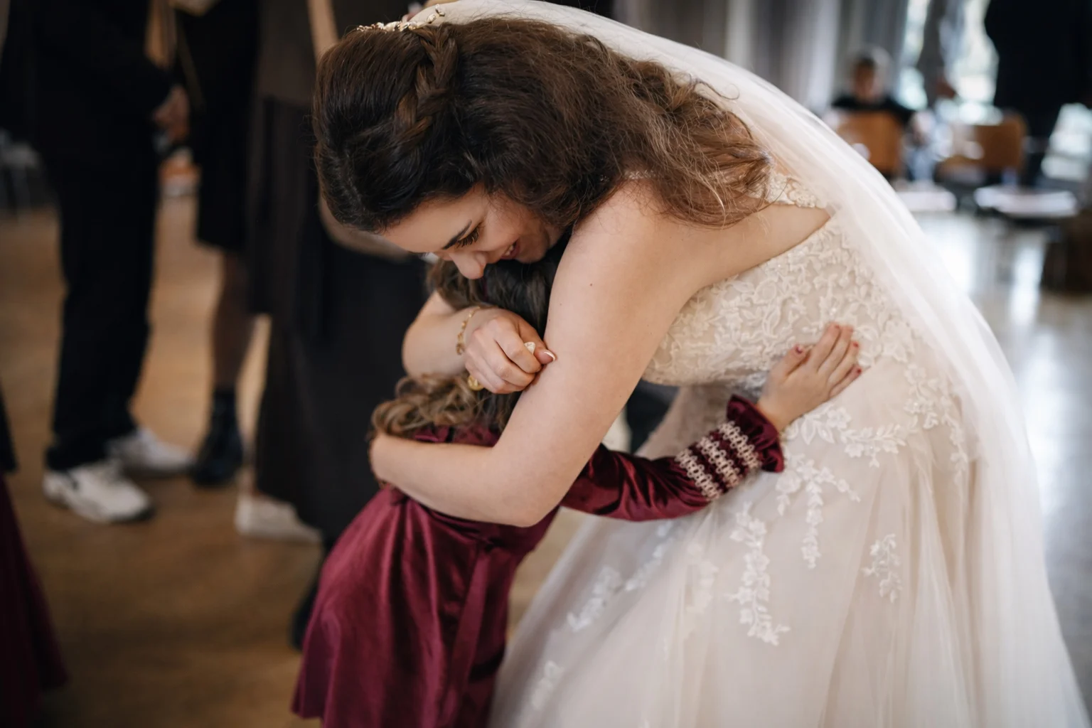 Bride in a wedding dress hugging a young child during an emotional moment at the wedding ceremony