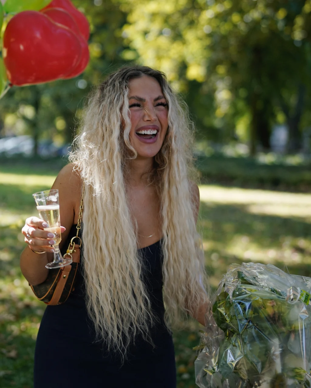 Happy wedding guest laughing and holding a glass of champagne and a bouquet during the celebration in Gelsenkirchen