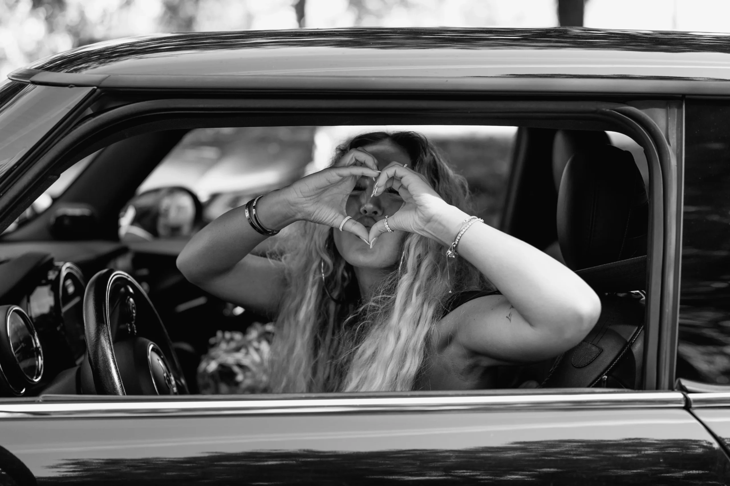Wedding guest making a heart shape with her hands from a car while greeting the couple in Gelsenkirchen