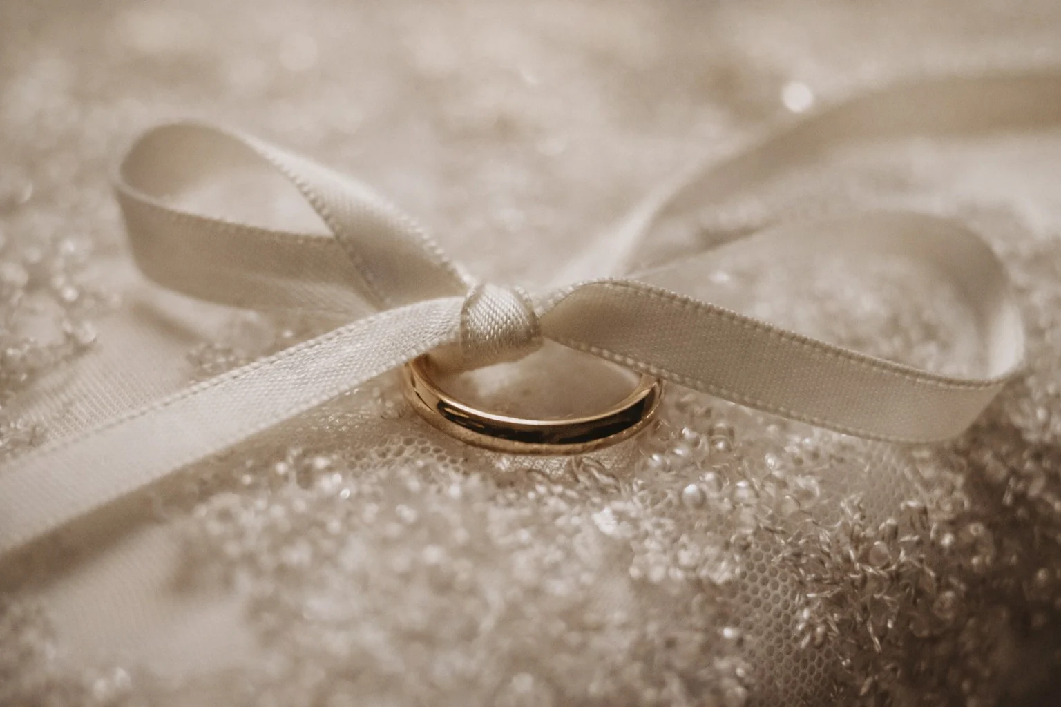 Close-up of a wedding ring tied with a silk ribbon on a bridal dress during wedding preparation in Düsseldorf, NRW, Germany
