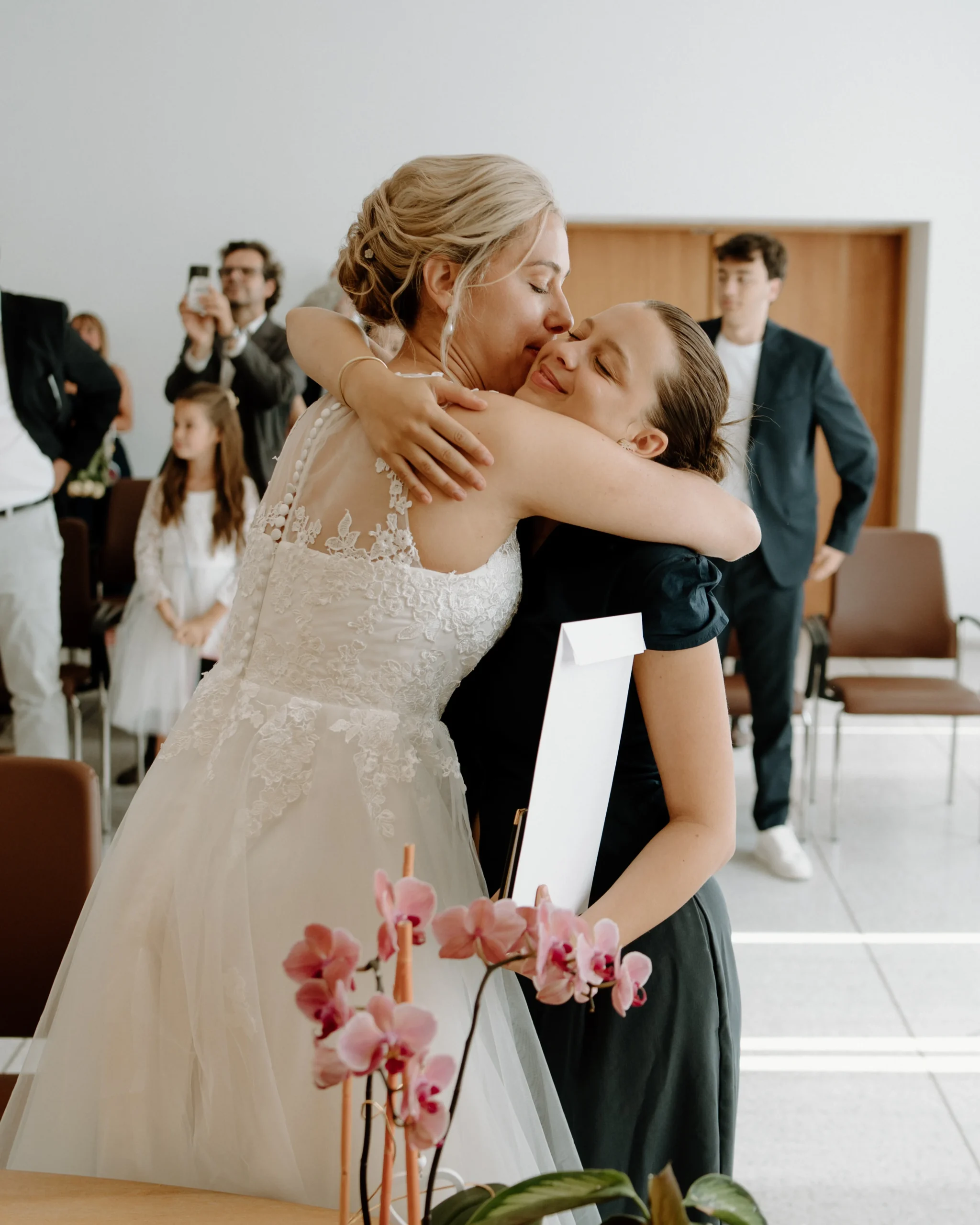 Braut küsst und umarmt eine Gratulantin nach der Trauung im Standesamt Köln, emotionaler Moment der Glückwünsche während einer intimen Hochzeitsfeier.