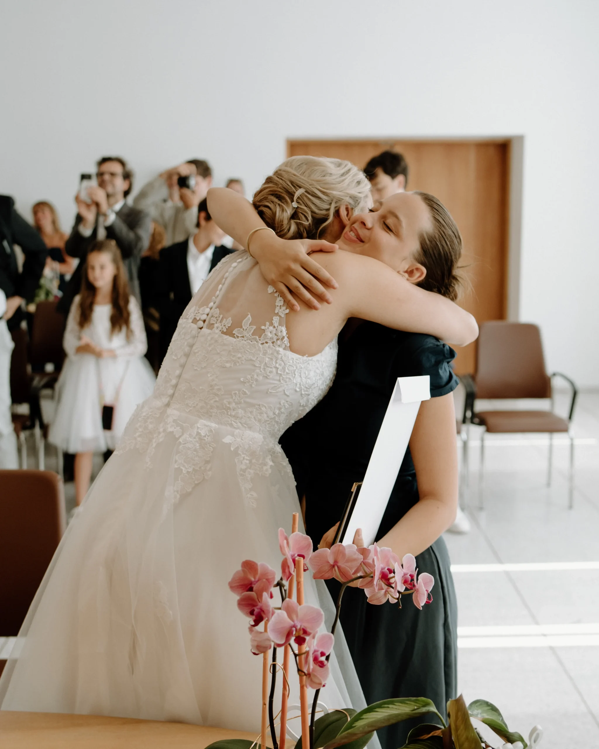 Braut umarmt herzlich eine Gratulantin nach der standesamtlichen Trauung in Köln, emotionale Gratulationen im Standesamt während einer intimen Hochzeit.