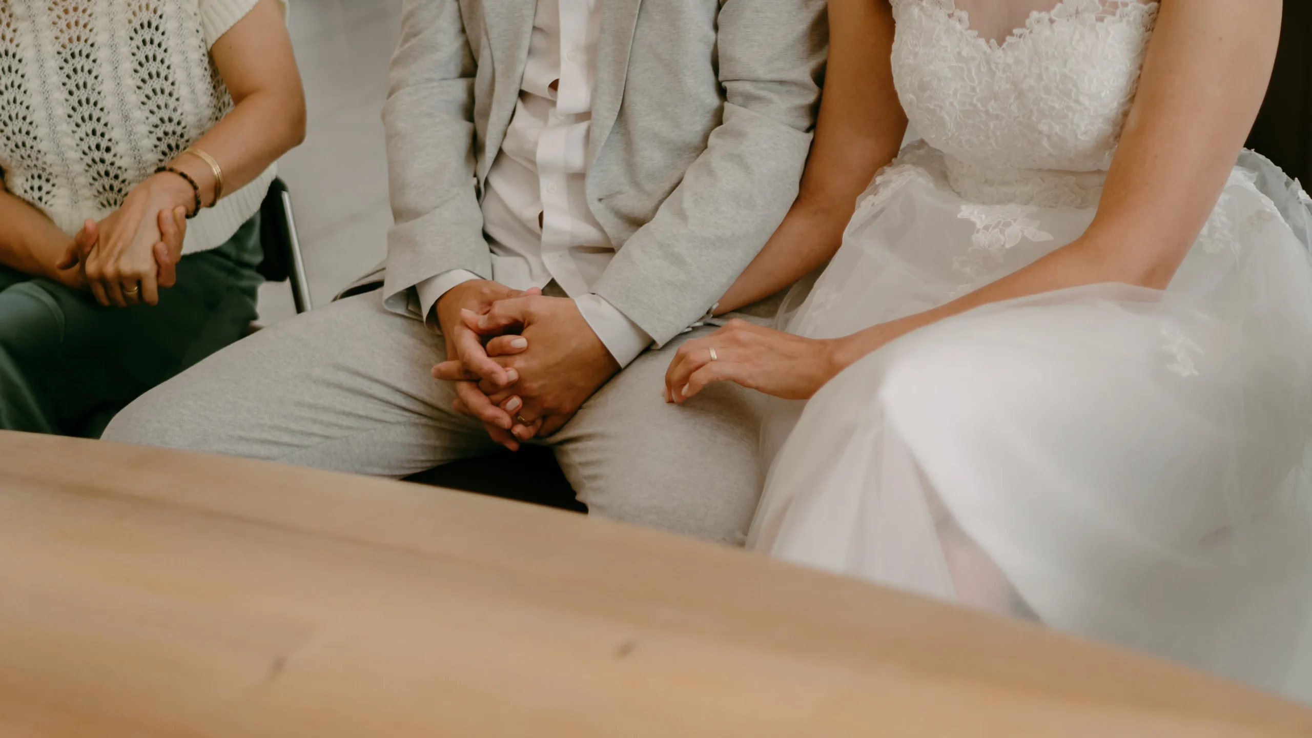 Nahaufnahme der Hände des Brautpaares während der standesamtlichen Trauung in Köln, Fokus auf Eheringe und emotionale Geste am Hochzeitstisch.