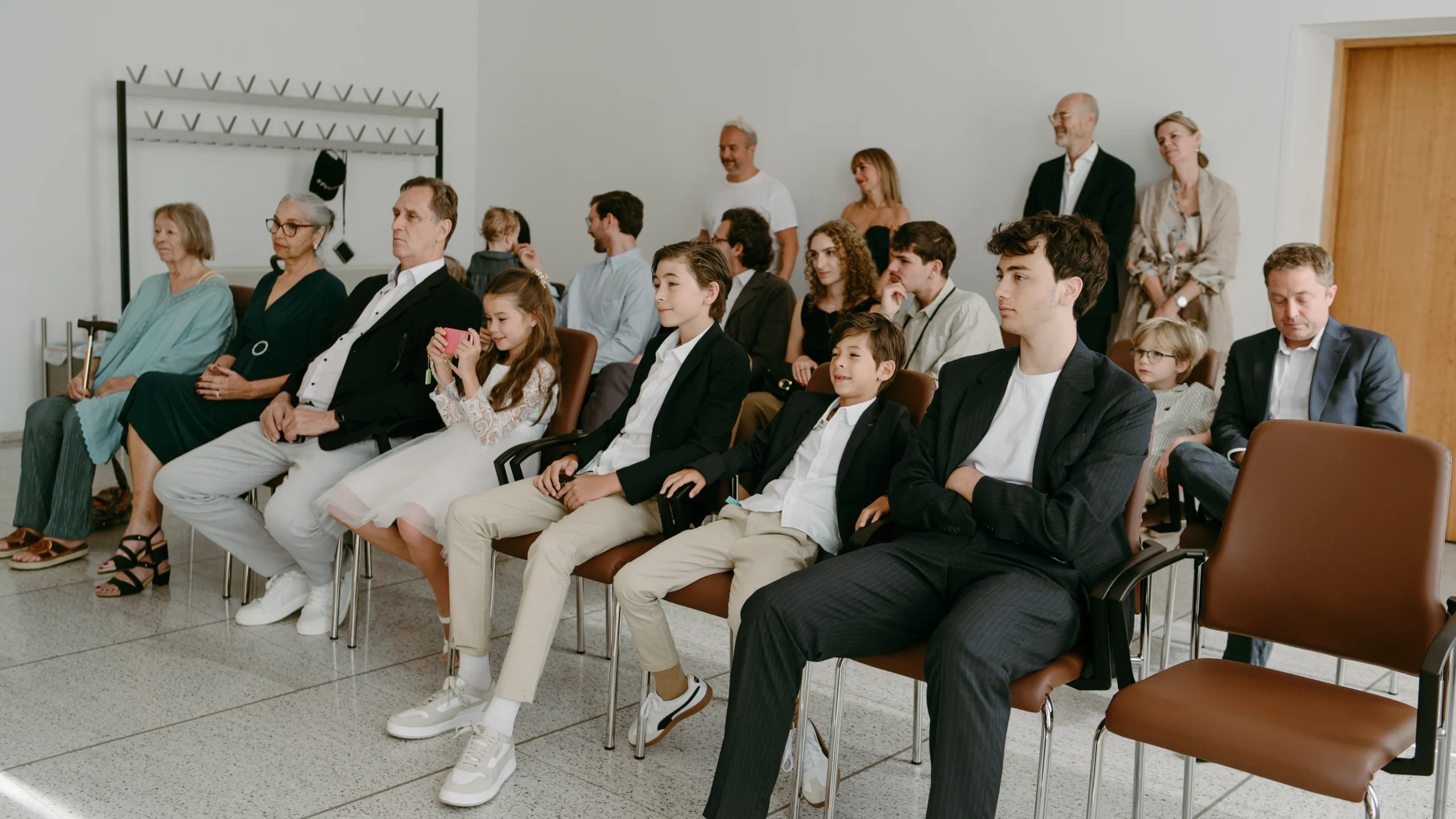 Blick aus der Perspektive der Hochzeitsgäste auf das moderne und helle Trauzimmer im Standesamt Köln, während sie auf den Beginn der Zeremonie warten.