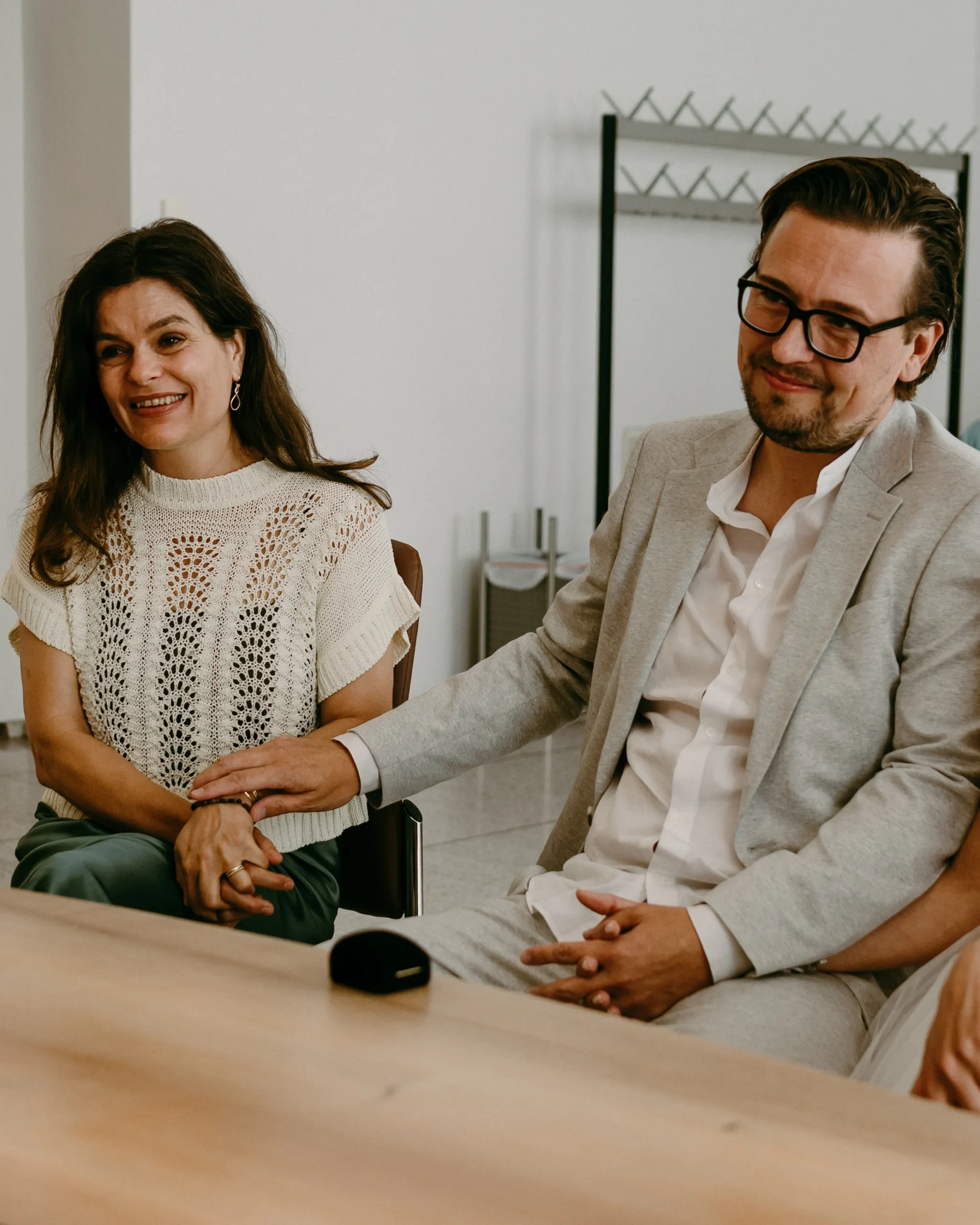 Ein emotionaler Moment im Standesamt Köln: Der Bräutigam hält die Hand seiner Trauzeugin während der Zeremonie in einem hellen, modernen Trauzimmer.