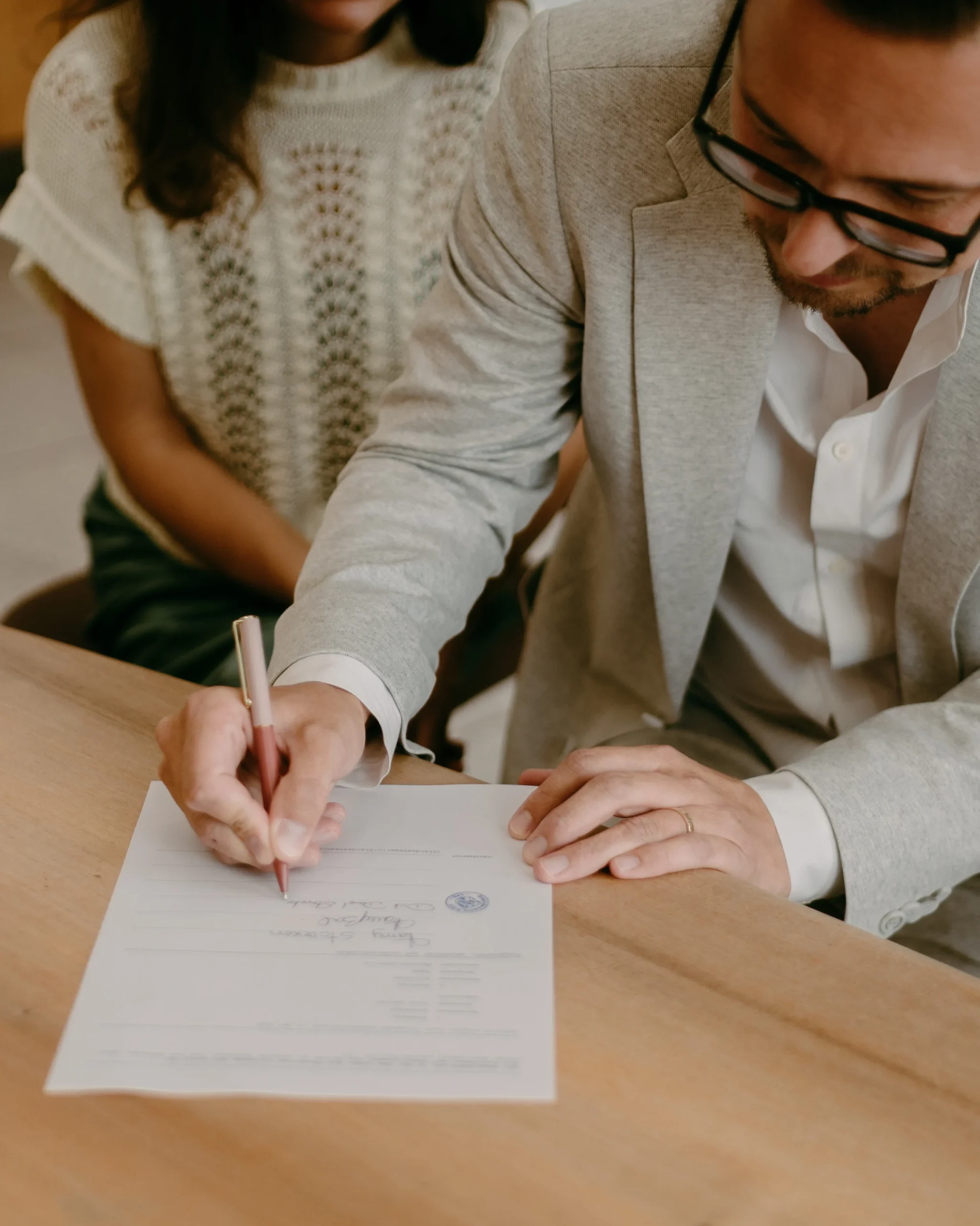 Nahaufnahme: Bräutigam unterschreibt die Eheurkunde während der standesamtlichen Trauung in Köln, Detailansicht der Unterschrift und des Eherings.