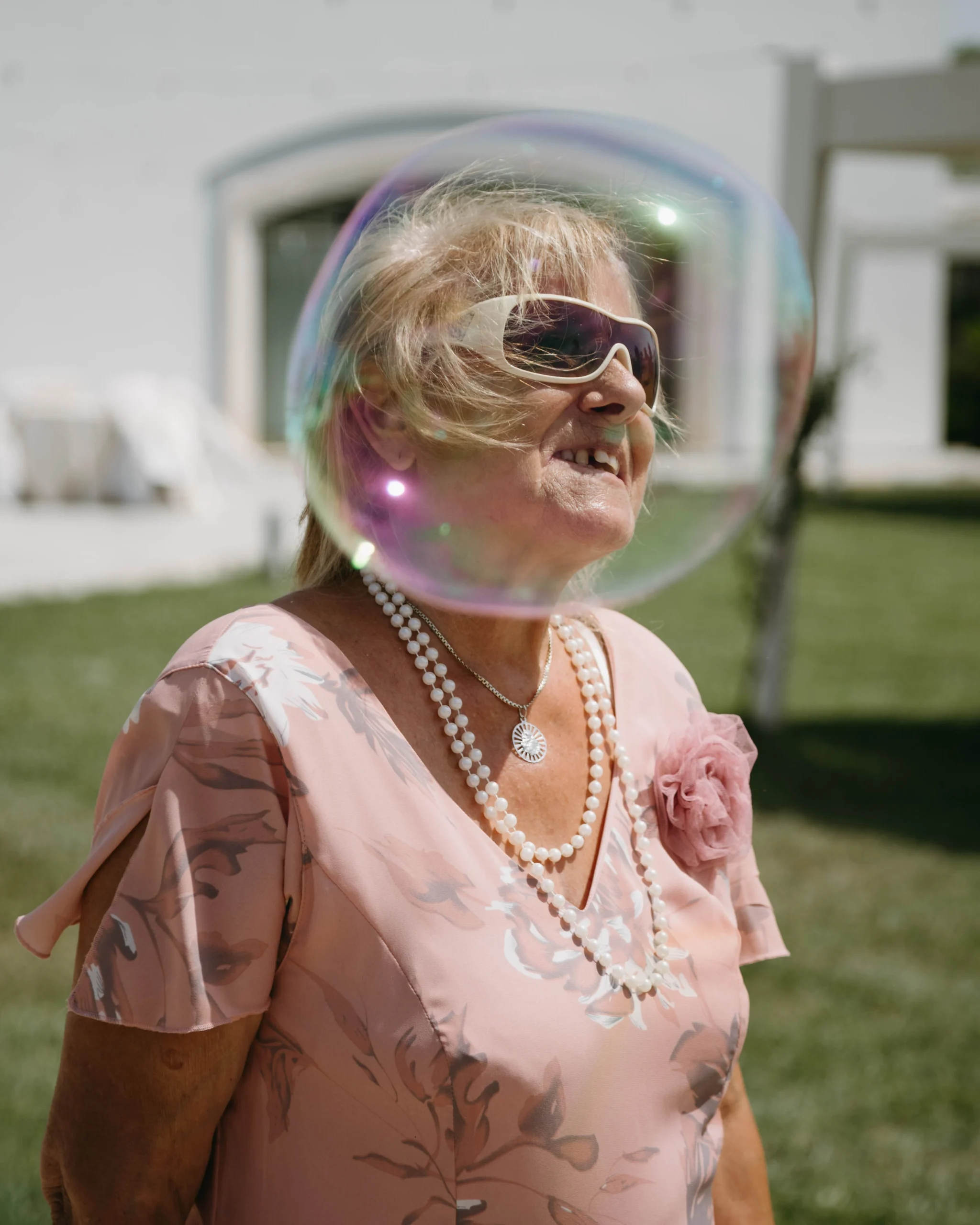 Ältere Hochzeitsgästin lächelt durch eine Seifenblase bei einer Hochzeit im Freien – authentische Hochzeitsreportage eines Hochzeitsfotografen in NRW Nordrhein-Westfalen
