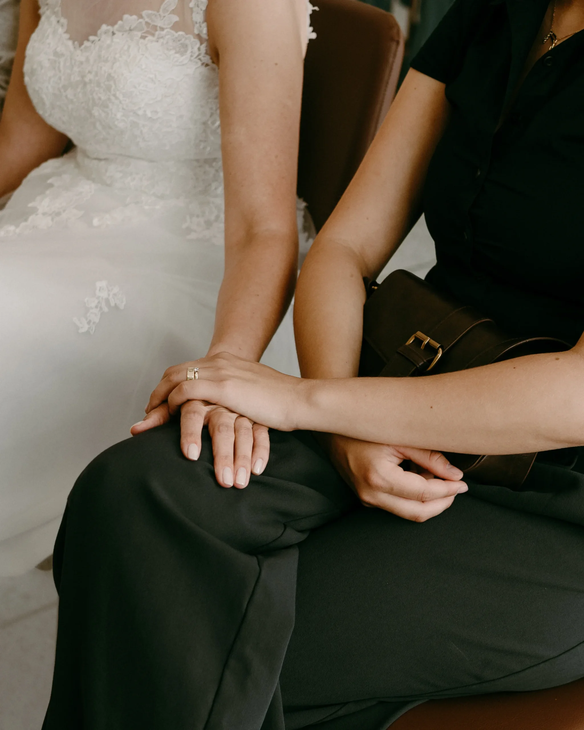 Detailaufnahme einer Braut im weißen Kleid, die während einer intimen standesamtlichen Trauung im Standesamt Köln die Hand einer nahestehenden Person hält – emotionale Hochzeitsreportage in Köln NRW.