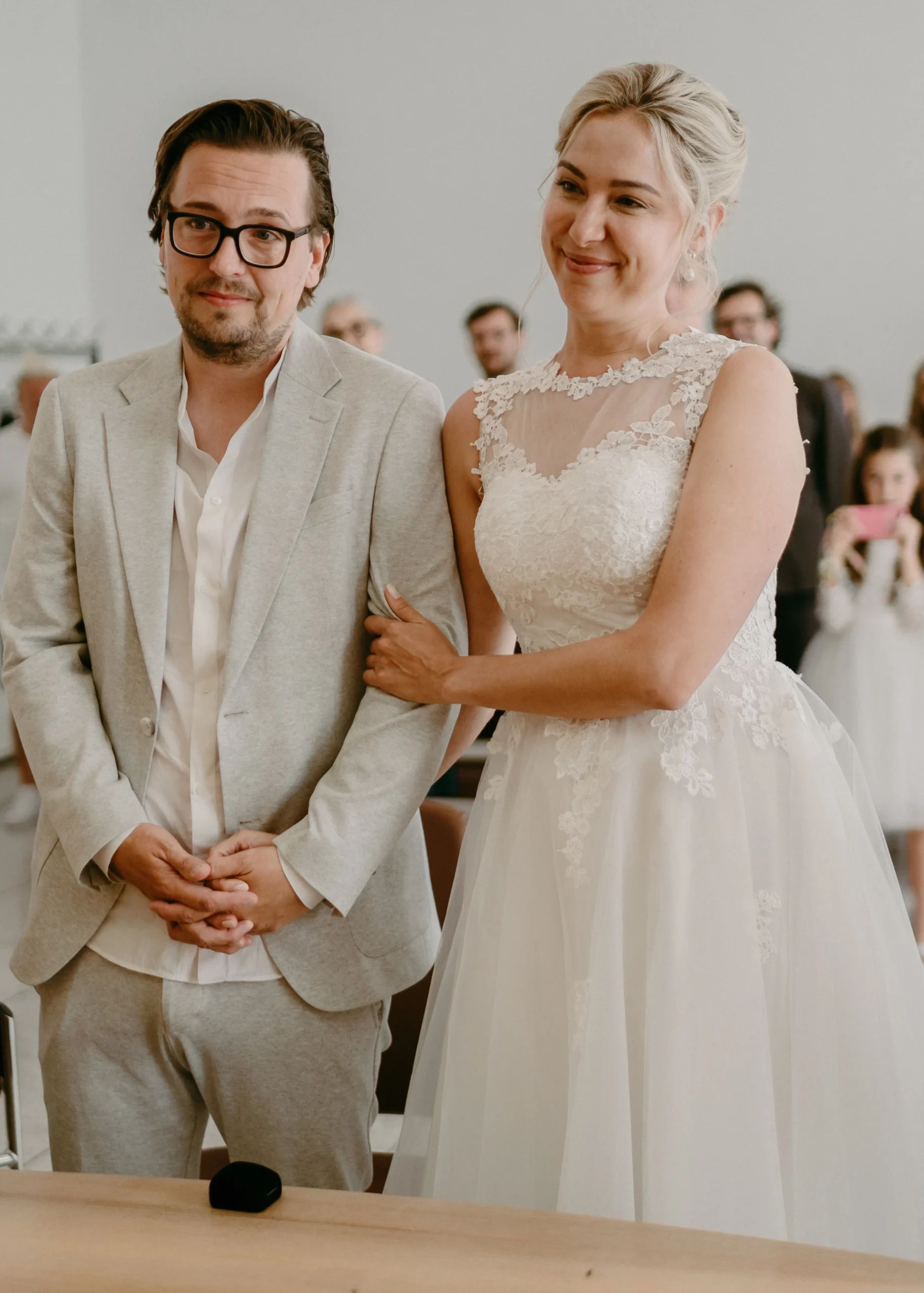 Nahaufnahme des Bräutigams, der während der standesamtlichen Trauung im Kölner Standesamt die offizielle Eheurkunde unterschreibt, umgeben von der Braut und der Standesbeamtin.