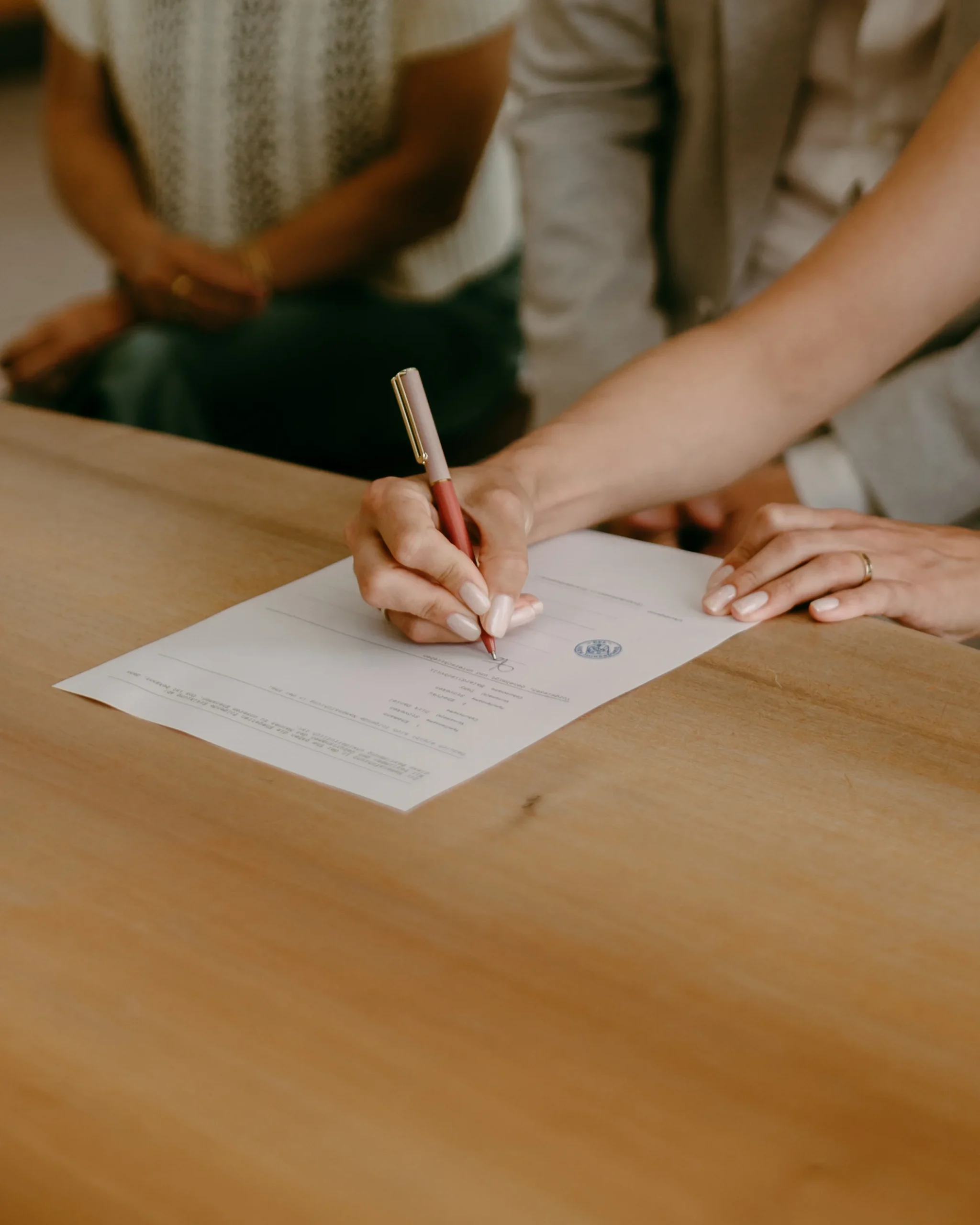 Braut unterschreibt die Heiratsurkunde während der standesamtlichen Trauung in Köln, Fokus auf das offizielle Dokument und die Hand mit Stift.