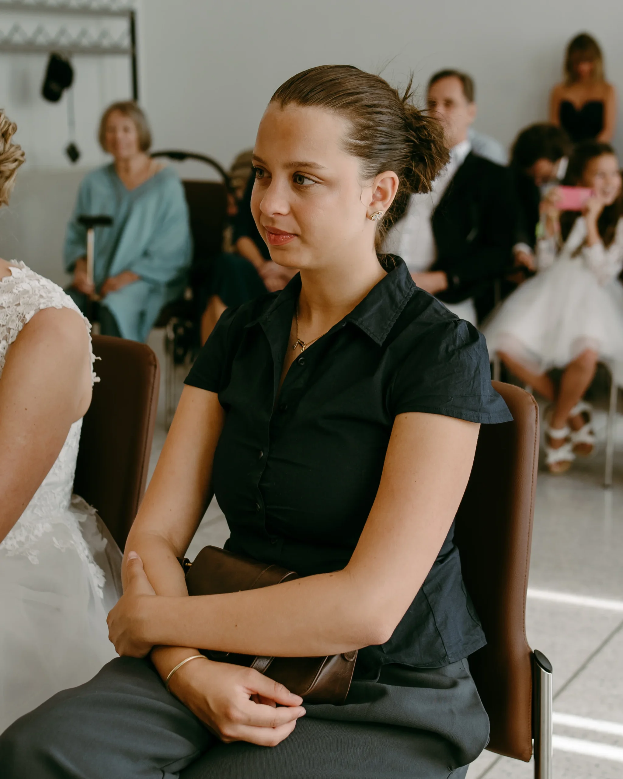 Porträt einer Trauzeugin, die während einer standesamtlichen Trauung im Kölner Standesamt aufmerksam zuhört, im Hintergrund sind weitere Hochzeitsgäste zu sehen.