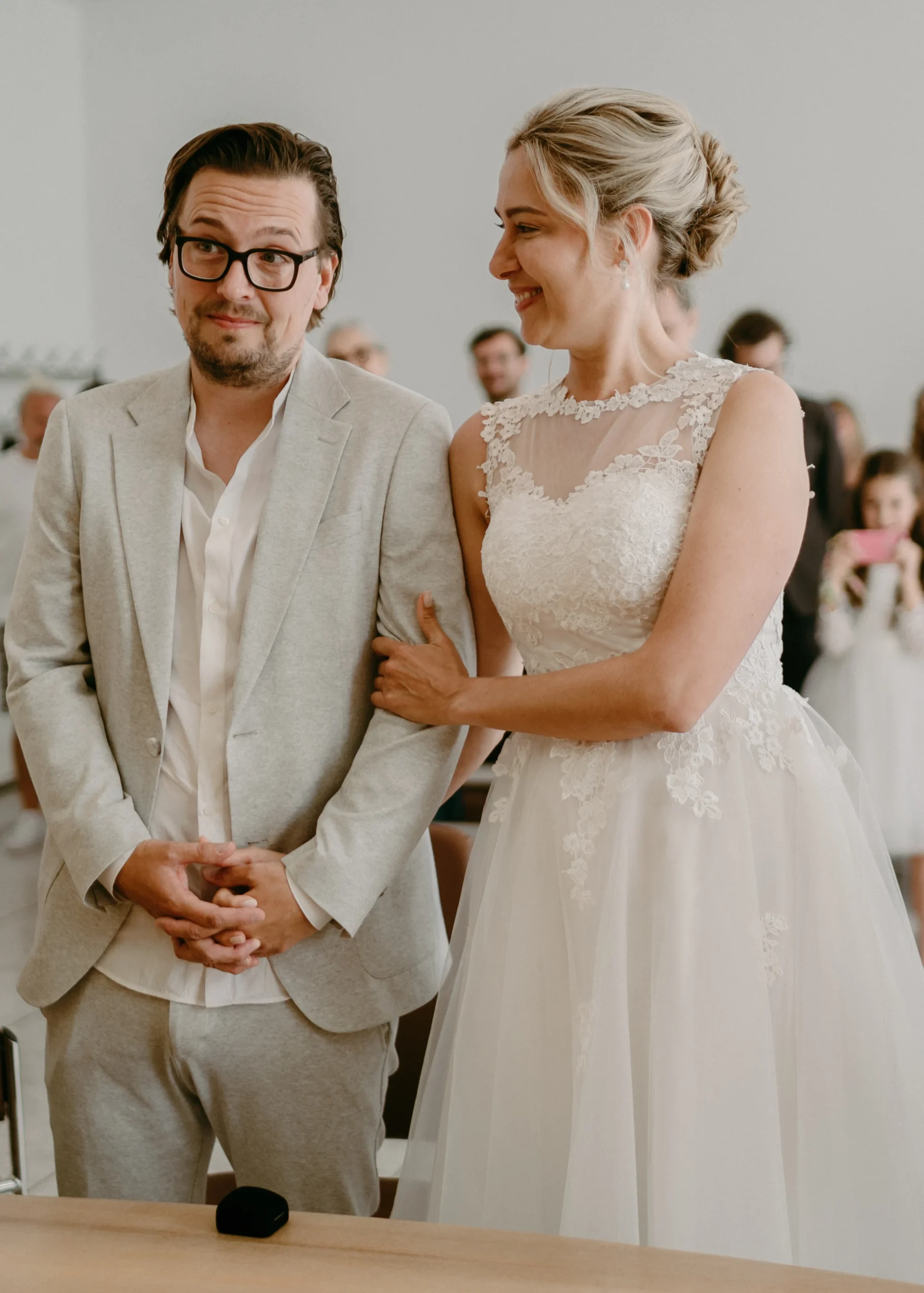 Die zweite Trauzeugin unterschreibt die Heiratsurkunde während der standesamtlichen Trauung im Kölner Standesamt, im Hintergrund das lächelnde Brautpaar.