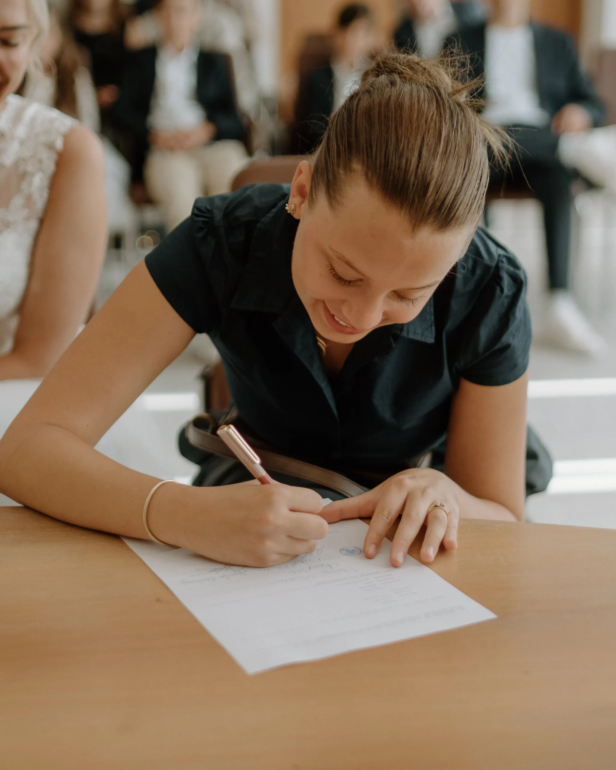 Lächelnde Trauzeugin unterschreibt das offizielle Protokoll im Standesamt Köln, authentischer Moment während einer intimen standesamtlichen Trauung.